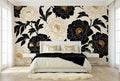 Black and gold peony wallpaper accent wall in a bright glamorous bedroom with a white upholstered bed gold accents and cream bedding