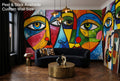 Colorful abstract cubist face wallpaper mural in a bold maximalist living room with black and gold furniture