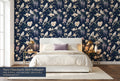 Navy chinoiserie bird and magnolia wallpaper in a bright dramatic bedroom with a white upholstered bed cream bedding brass accents and warm candlelight