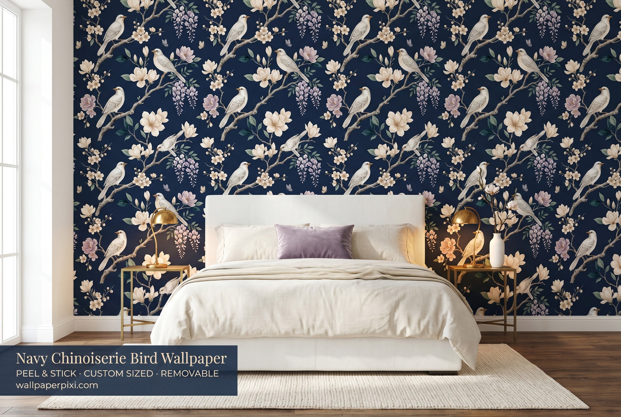 Navy chinoiserie bird and magnolia wallpaper in a bright dramatic bedroom with a white upholstered bed cream bedding brass accents and warm candlelight