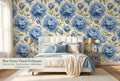 Blue peony floral wallpaper in a bright romantic bedroom with a white upholstered bed blue and cream bedding brass accents and warm morning light