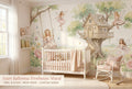 Fairy ballerina treehouse wall mural in a bright girls nursery with a white crib blush pink bedding and warm natural light.