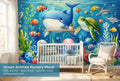 Ocean animals underwater wall mural in a bright boys nursery with a white crib ocean blue bedding and natural wood accessories.