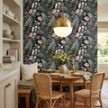 Dark botanical wallpaper featuring a small perched songbird, ivory star flowers, soft blush daisies, sage and teal ferns, silver-blue leaves, and fine berry stems on a deep charcoal-black painterly ground — premium dark cottagecore wallpaper by WallpaperPixi