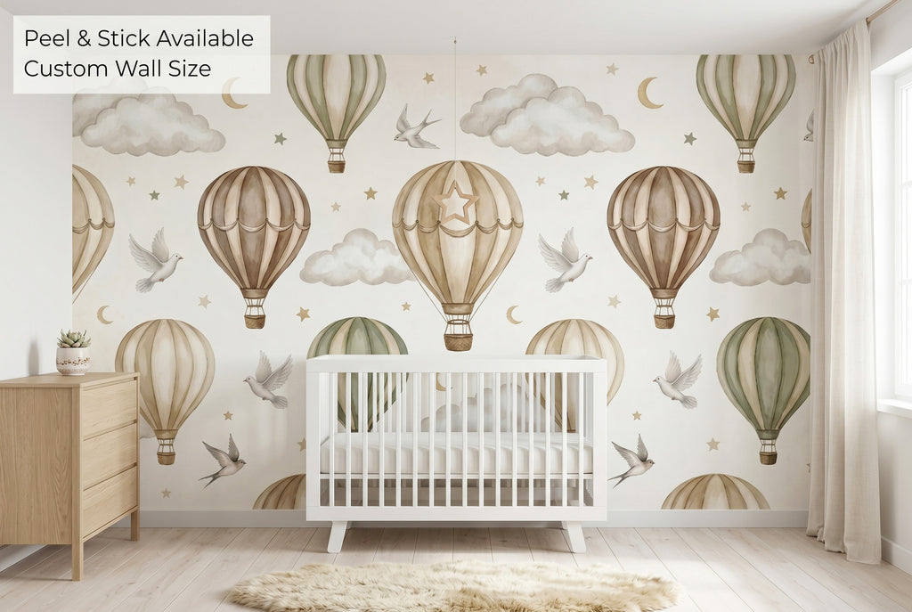Neutral hot air balloon wall mural in beige and taupe on the full feature wall of a clean Scandinavian nursery — the wide panoramic sky scene with white doves and gold crescent moons behind a white slatted crib, natural oak dresser and sheepskin rug.