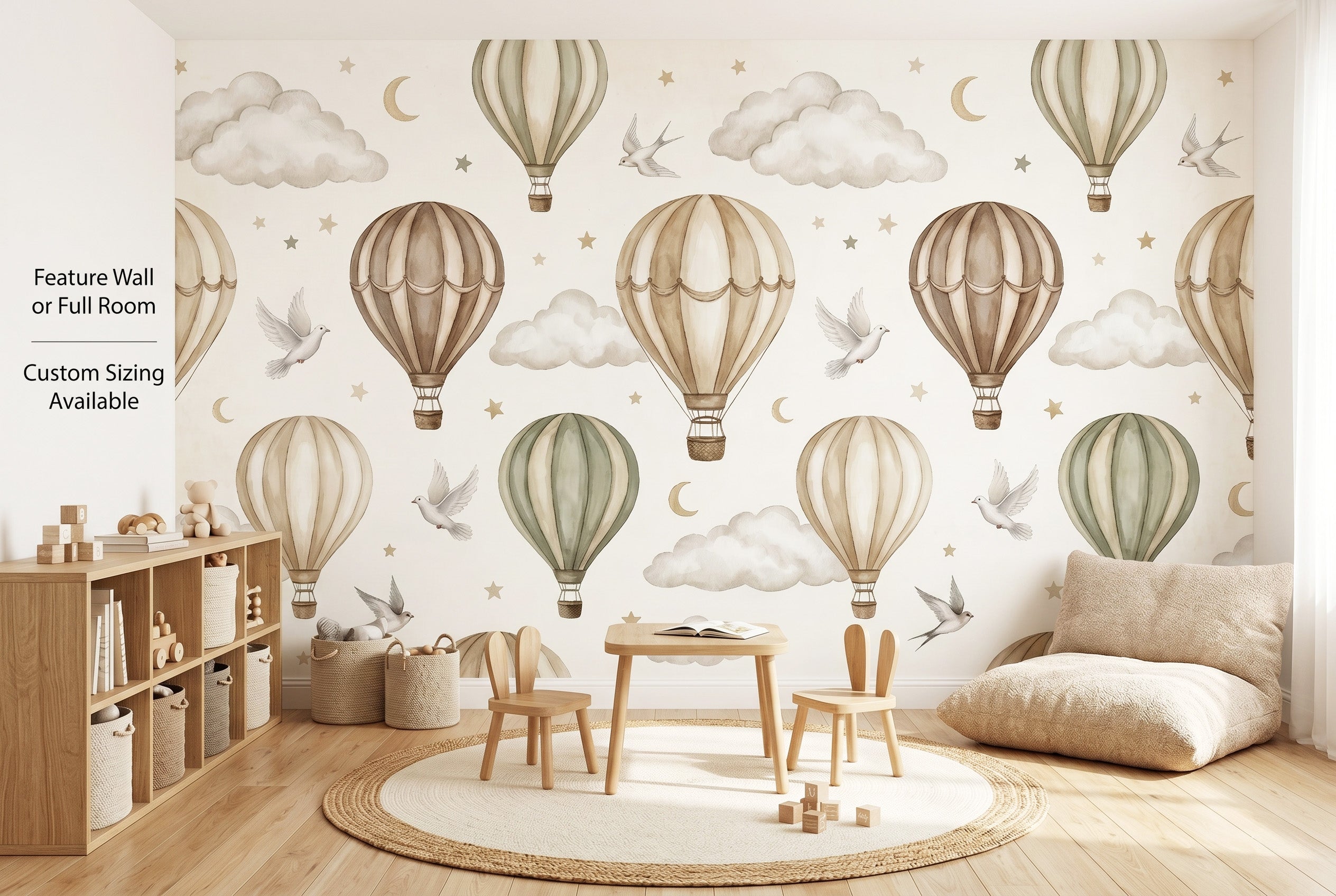 Neutral hot air balloon wall mural spanning the full back wall of a gender-neutral playroom as a wide panoramic scene — beige, taupe and sage balloons with white doves and gold crescent moons above wooden toy shelves, a round cream rug and small wooden play table.